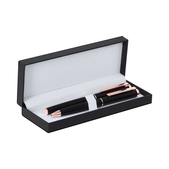 Distinguido set de bolígrafo y roller, con cuerpos diseñados en elegante aluminio de acabado negro mate y detalles decorativos en oro rosado. Ambos presentan una estilizada caña y clip metálico. El bolígrafo cuenta con un mecanismo giratorio. El roller incluye capucha. Ambos con tinta azul y cartucho jumbo. Presentados en un sofisticado estuche negro con tacto de piel e interior blanco.