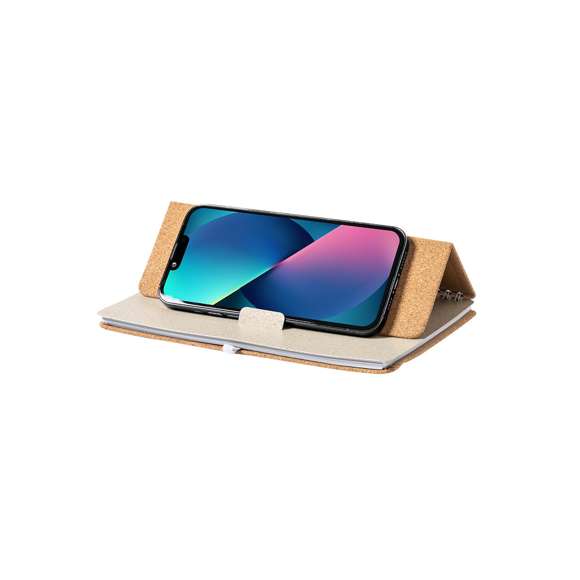 Libreta soporte de anillas de línea nature. Tapas rígidas fabricadas en corcho natural, con original soporte en caña de trigo para smartphone y tablet. Incluye elástico de cierre y soporte para bolígrafo en color blanco. 70 hojas interiores con disposición a una raya. Presentada en bolsa individual de diseño.