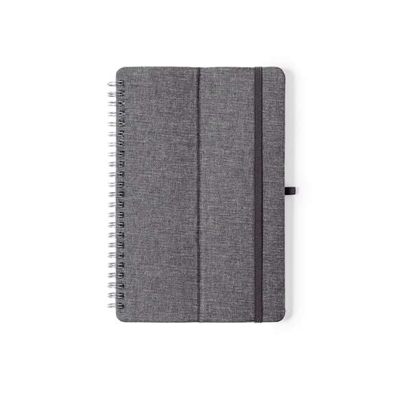  	Libreta soporte de anillas de línea nature. Tapas rígidas fabricadas en resistente material RPET 300D, elaborado a partir de plástico reciclado. Con original soporte para smartphone y tablet integrado en la portada y fabricado en caña de trigo. Incluye elástico de cierre y soporte para bolígrafo a juego. 70 hojas interiores con disposición a una raya y disponible en variada gama de colores. Con distintivo RPET en contraportada y presentada en bolsa individual reciclada.