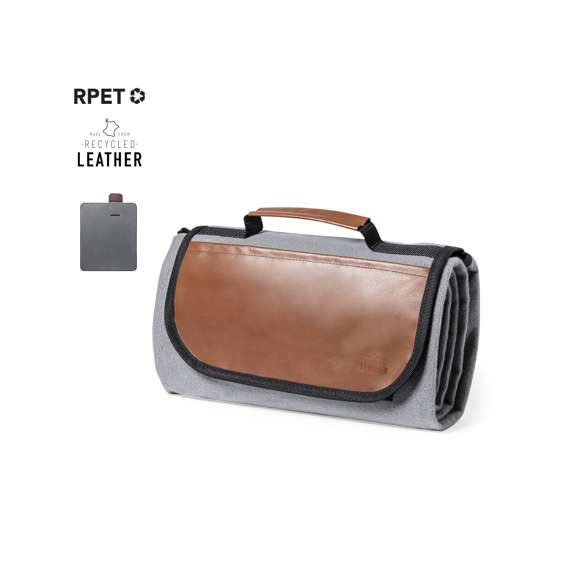 Manta de picnic premium fabricada en resistente poliéster RPET de 160g/m2 y acabado en gris. Plegable y con cierre de velcro  solapa y asa en cuero reciclado con ribetes reforzados. En tamaño 120x150 cm, con base aislante en PEVA y lado para sentarse de agradable tacto. De fácil plegado y tamaño compacto, con distintivo cuero reciclado en la solapa. El material RPET se elabora a partir de plástico reciclado, para así fomentar la reutilización de residuos plásticos y ayudar a la sostenibilidad del planeta.El cuero reciclado rescata las fibras desechadas en los procesos de fabricación del cuero, minimizando el desperdicio de material, contribuyendo a reducir el impacto ambiental y manteniendo a la vez sus propiedades originales.