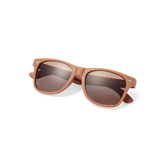 Gafas de sol de línea nature con protección UV 400. Montura fabricada en fibra de café y patillas en madera natural a juego, con lentes en tono marrón. Distintivo fibra de café inyectado en molde de patilla izquierda. Presentación en caja individual de diseño kraft.La fibra de café es una solución circular que se obtiene de la utilización de los residuos producidos en la obtención del café. Una alternativa sostenible que favorece la reducción del uso de plásticos, ahorrando energía en su proceso de fabricación y contribuyendo al cuidado del medio ambiente.