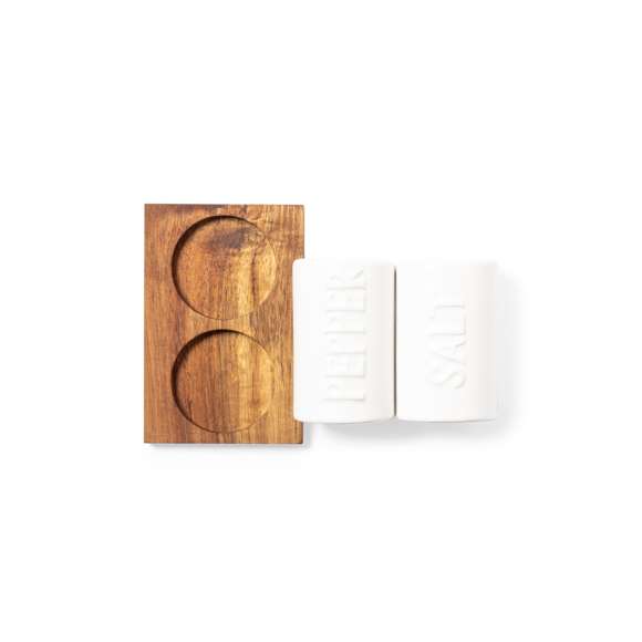  	Set de salero y pimentero en blanco y fabricados en cerámica. Incluye base en madera natural de acacia, troquelada para encajar el salero y el pimentero. Presentación en caja individual de diseño kraft.