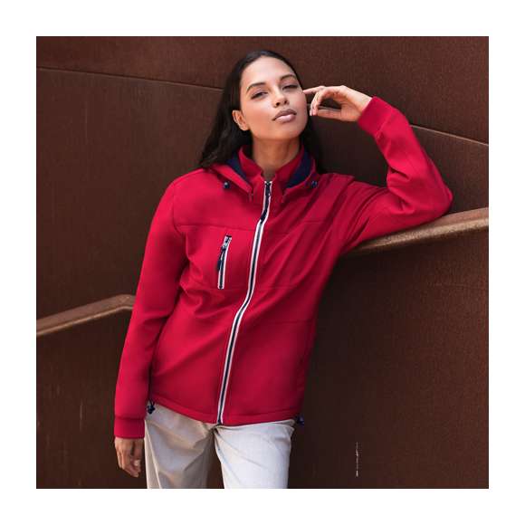 Chaqueta de resistente y transpirable material soft shell de 300g/m2. De corte moderno, con cremallera central, bolsillos laterales y práctico bolsillo en pecho con cierres de cremallera y tiradores en contraste. Cuello elevado con capucha ajustable y desmontable. Dobladillo inferior con cordón ajustable. Mangas con cómodos puños de punto en color a juego. Exterior en soft shell resistente al viento y al agua, e interior de cálido micropolar en color contraste. Disponible en tallas XS, S, M, L, XL, XXL.