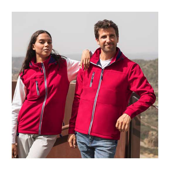 Chaqueta de resistente y transpirable material soft shell de 300g/m2. De corte moderno, con cremallera central, bolsillos laterales y práctico bolsillo en pecho con cierres de cremallera y tiradores en contraste. Cuello elevado con capucha ajustable y desmontable. Dobladillo inferior con cordón ajustable. Mangas con cómodos puños de punto en color a juego. Exterior en soft shell resistente al viento y al agua, e interior de cálido micropolar en color contraste. Disponible en tallas XS, S, M, L, XL, XXL.