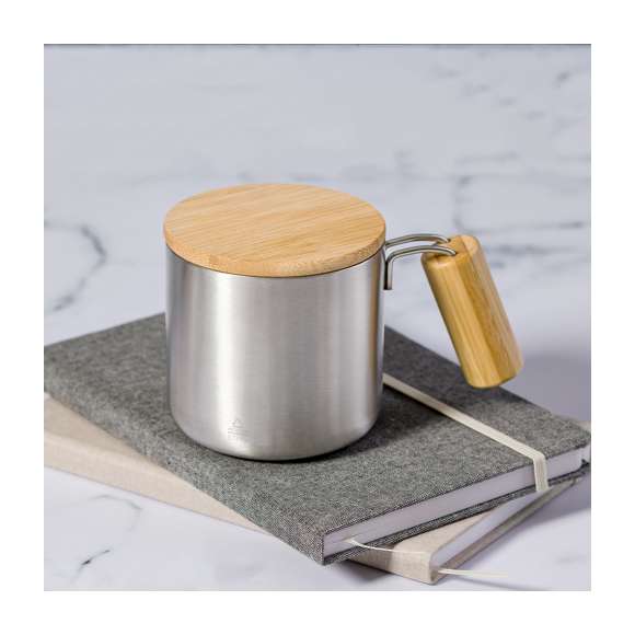 Original taza térmica de doble pared y 330 ml de capacidad. Fabricada en acero inox reciclado, con tapa de bambú y asa de cómodo agarre a juego. Con distintivo Acero Inoxidable Reciclado. Presentada en caja individual de diseño kraft y en bolsa reciclada.El acero es uno de los materiales más demandados y que puede encontrarse casi en todas partes, desde productos de uso diario a grandes construcciones. Con innumerables propiedades, entre las que cabe destacar la durabilidad y su alto grado de reutilización, convirtiéndolo en una alternativa muy valorada en soluciones de sostenibilidad. Debidamente tratado, permite obtener nuevos recursos de infinita utilización.