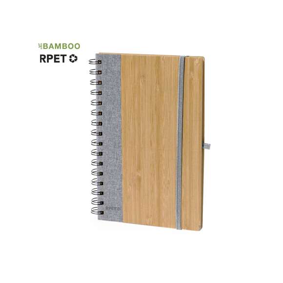 Libreta de anillas con tapas rígidas de bambú. Incluye 80 hojas con disposición a una raya de papel reciclado. Con cierre elástico, banda lateral, y soporte para bolígrafo a juego. Disponible en variada gama de colores, presentada individualmente en bolsa de papel reciclado. Materiales como el bambú fomentan la utilización de materias primas naturales, reduciendo las emisiones contaminantes. Proviene de una planta de gran resistencia y versatilidad, con crecimiento y regeneración rápidos, siendo una excelente alternativa al uso de madera tradicional.