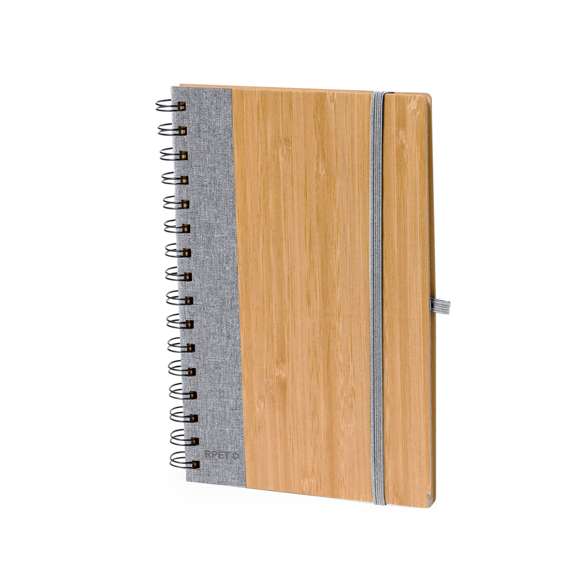 Libreta de anillas con tapas rígidas de bambú. Incluye 80 hojas con disposición a una raya de papel reciclado. Con cierre elástico, banda lateral, y soporte para bolígrafo a juego. Disponible en variada gama de colores, presentada individualmente en bolsa de papel reciclado. Materiales como el bambú fomentan la utilización de materias primas naturales, reduciendo las emisiones contaminantes. Proviene de una planta de gran resistencia y versatilidad, con crecimiento y regeneración rápidos, siendo una excelente alternativa al uso de madera tradicional.
