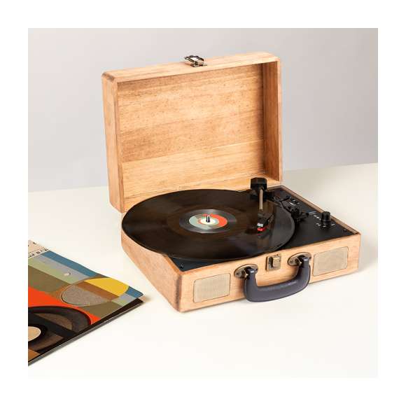 Tocadiscos portátil presentado en un maletín fabricado en madera natural, con cierre de seguridad y asa de transporte. Compatible con discos de 33, 45 y 78 RPM y con adaptador central para singles de 7”. Brazo recto, con función de recogida automática cuando llega al final de cada cara del disco y funda protectora para la aguja cuando no se está usando. Conexión por Bluetooth@ y altavoces estéreo integrados de 3W de potencia, con función reproductor para conectar una memoria USB. Además, ofrece la posibilidad de digitalizar los discos de vinilo de manera sencilla. Salida estéreo RCA para conectar a dispositivos de sonido externos y botón ON/OFF con control de volumen. Incluye una batería interna de 1.200 mAh, pudiendo usarse en cualquier lugar sin necesidad de conectarlo a la red (cable de carga incluido). Viene en caja individual de diseño kraft, con manual de instrucciones en español e inglés.