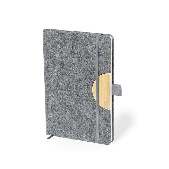 Bloc de notas con soporte de tapas rígidas fabricado en fieltro RPET 300D. Con original soporte para smartphone y tablet integrado en la portada, fabricado en bambú. Incluye elástico de cierre y soporte para bolígrafo a juego, con 80 hojas interiores de disposición a una raya. Con logotipo RPET en contraportada y presentada en bolsa individual reciclada.El fieltro RPET es fruto de la combinación del proceso de reciclaje de materiales plásticos junto con la técnica milenaria de fabricación del fieltro, dando como resultado un material de eco-tendencia que, además de ser de origen reciclado, también se convierte en reciclable.