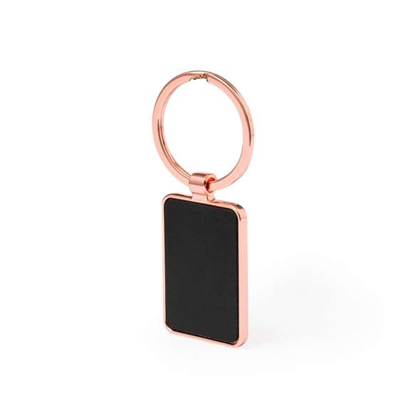 Llavero metálico de sofisticado diseño, con recubrimiento de cobre galvanizado y acabado brillo. Forrado en elegante polipiel en una de sus caras y disponible en diseño rectangular y circular. Presentado individualmente bolsa de papel reciclado.