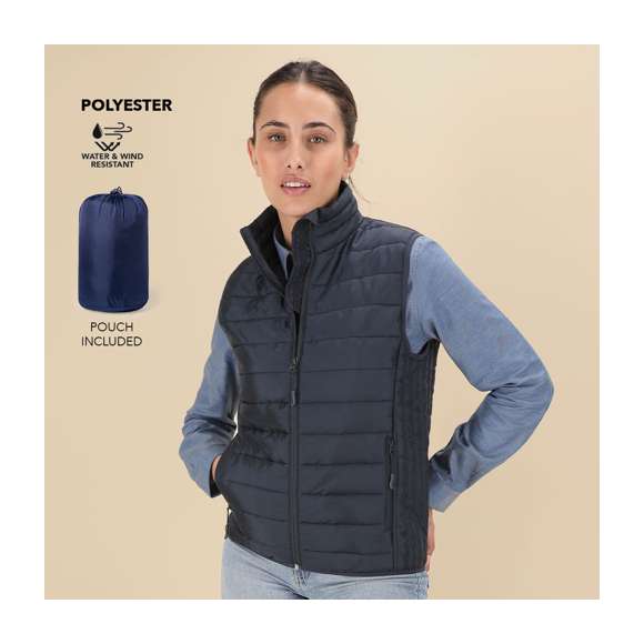 Chaleco acolchado de mujer en material extra ligero, compacto y de corte entallado. Resistente al agua y cortavientos, con suave relleno y forro interior. Cierre de cremallera invertida y tirador a juego. Cuenta con 2 bolsillos laterales con cremalleras y tirador a juego y 2 bolsillos interiores. Sisa y cintura con ribete elástico a tono. Incluye práctica funda de transporte.