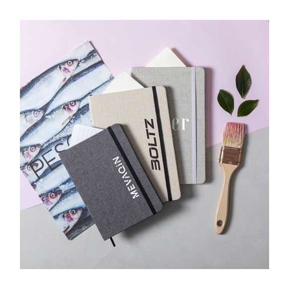 Bloc de notas de materiales naturales. Tapas en suave algodón de color crudo, con elástico de cierre y marcapáginas a juego en vivos colores. Incluye 80 hojas lisas.