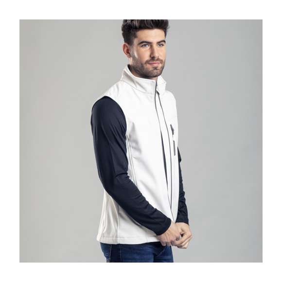 Chaleco impermeable y transpirable en material soft shell de 300g/m2. De elegante diseño bicolor, en color blanco con contraste de detalles en gris. Cierre de cremallera y bolsillos frontal y laterales de cremallera. Disponible en tallas S, M, L, XL, XXL.