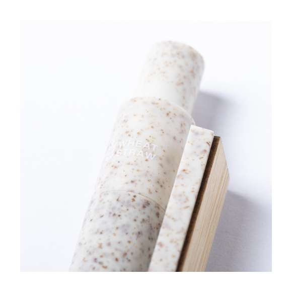 Bolígrafo de línea nature y mecanismo pulsador. Cuerpo fabricado en combinación de caña de trigo y clip en bambú, para así fomentar la utilización de materias primas naturales y reducir las emisiones contaminantes. Clip con amplia zona de marcaje y en tinta azul. Distintivo caña de trigo en la parte superior del bolígrafo.