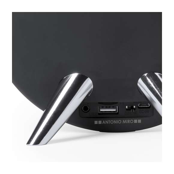 Altavoz de conexión Bluetooth® en elegante acabado de color negro con accesorioss en plateado y original diseño circular. Ofrece 8W de potencia, tiene función de manos libres, una ranura para tarjetas micro SD de hasta 32 GB de capacidad y entrada auxiliar de línea mediante conexión jack de 3,5mm. Compatible con iOS y Android, incluye cable de carga mini USB, cable auxiliar jack de 3,5mm y viene presentado en atractiva caja de diseño. Con soportes de goma antideslizantes en la base.