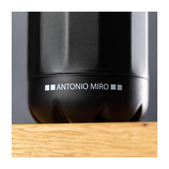 Bidón en acero inox de Antonio Miró. De 750ml de capacidad y sobrio acabado en negro satinado, con cuerpo prisma y logotipo de la marca en la base. Con tapón cromado a rosca y presentado en atractiva caja de diseño con logotipo de la marca.