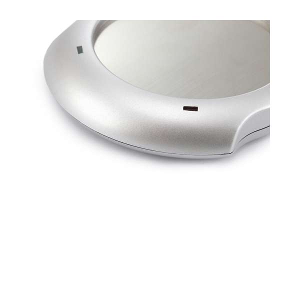 Calentador de tazas con conexión USB y de superficie metálica, especialmente diseñada para mantener el calor. De elegante diseño en color gris y compatible con tazas de hasta 7,4cm de diámetro, incorpora interruptor en la parte trasera y luces de estado. Presentada en caja individual.