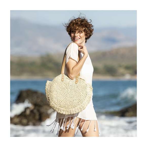 Bolso de desenfadado diseño en rafia sintética y con forma circular, un must. Compartimento principal de cierre de cremallera y tirador metálico, con bolsillo en el interior. Forro interior y asas largas en PU, con triple refuerzo en X y superficie para personalización en madera, especialmente diseñada para marcaje en láser.
