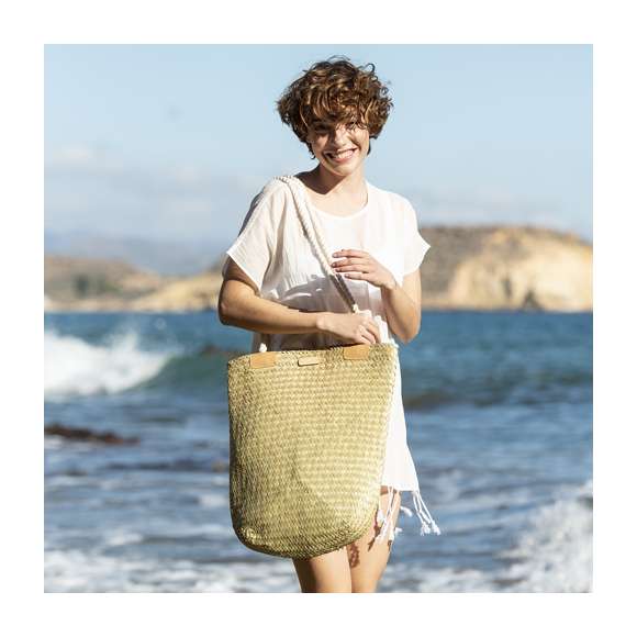 Bolso de desenfadado diseño en paja y con forma rectangular, un must. De gran capacidad y con originales asas largas en algodón, reforzadas en PU. Con superficie para personalización en madera, especialmente diseñada para marcaje en láser.