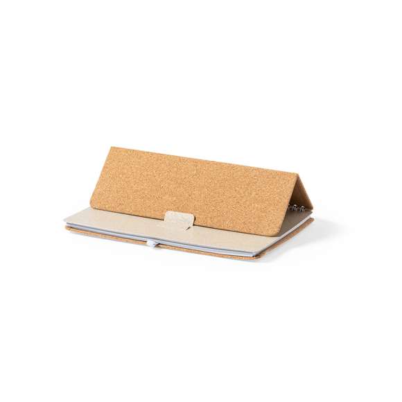 Libreta soporte de anillas de línea nature. Tapas rígidas fabricadas en corcho natural, con original soporte en caña de trigo para smartphone y tablet. Incluye elástico de cierre y soporte para bolígrafo en color blanco. 70 hojas interiores con disposición a una raya. Presentada en bolsa individual de diseño.