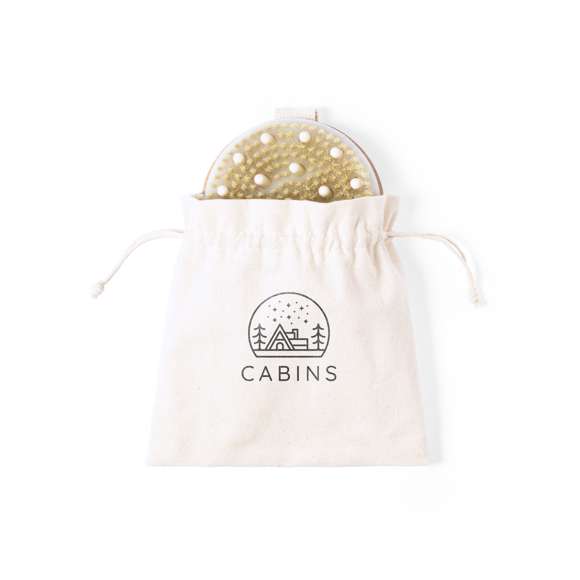 Cepillo exfoliante masajeador fabricado en madera natural, con cinta para sujeción a juego. Presentado en bolsa de algodón crudo 100% natural, con cierre de cordón