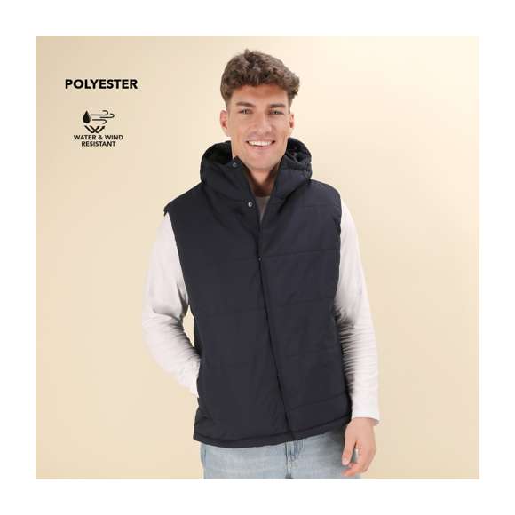 Chaleco con capucha, en cálido y suave material 100% poliéster. En material ligero, resistente al viento y al agua. Diseño de elegante construcción horizontal y acolchado, con capucha fija integrada. Doble cierre frontal de cremallera y corchetes. Bolsillos laterales con tiradores a juego y cordón ajustable en dobladillo. Disponible en tallas XS, S, M, L, XL, XXL.