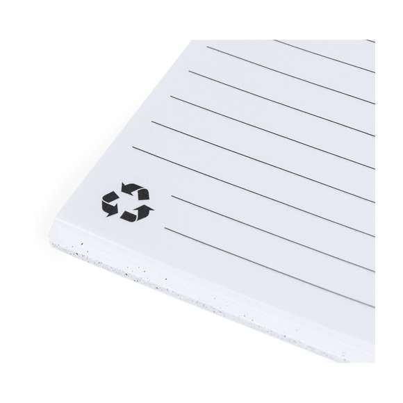 Set de libreta y bolígrafo. Libreta de anillas con tapas rígidas fabricadas en RABS y bolígrafo a juego. De tamaño A5, con elástico de cierre elegante disponible en amplia variedad de colores. Interior con 70 hojas blancas con disposición a una raya. Bolígrafo de mecanismo pulsador en RABS con tinta azul. Incluyen distintivo RABS. Presentado en bolsa individual reciclada.