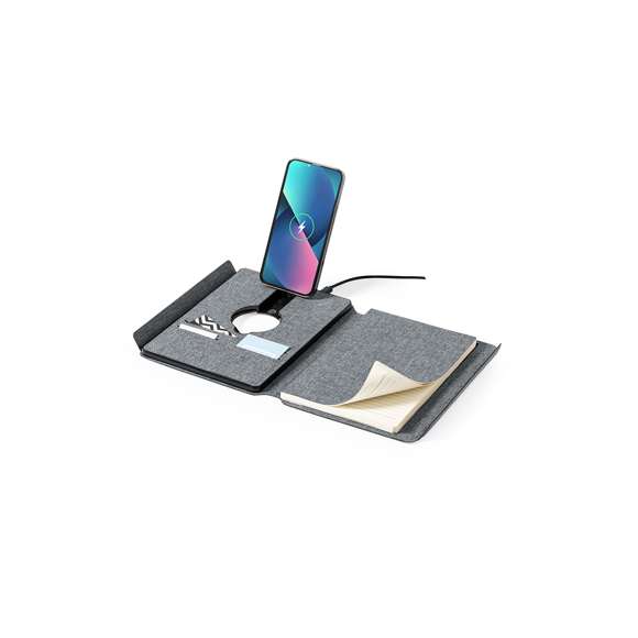 Carpeta/bloc multifunción con cierre magnético fabricada en poliéster 300D RPET, elaborado a partir de plástico reciclado, y etiqueta interior con distintivo RPET.Cargador inalámbrico de 10W, con fijación magnética y multiposición, integrado en portada, que permite usar el dispositivo mientras se está cargando. Accesorio anillo adhesivo incluido, compatible con todos los dispositivos equipados con tecnología Magsafe y Qi. Con cargador inalámbrico para smartwatch en la contraportada interior.Batería integrada de 5.000 mAh de capacidad de carga, con puerto Tipo C de entrada/salida y LEDs indicadores de estado de carga, con cable cargador incluido.Interior con soporte para smartphone y multitud de compartimentos para tarjetas. Soporte para bolígrafo y bloc interior A5 de 64 hojas, con disposición a una raya.Presentada en atractiva caja individual de diseño.Las capacidades mostradas en todas nuestras baterías auxiliares externas son reales, incorporando todas ellas baterías de grado A y no recicladas, con una vida útil de al menos 500 ciclos de carga y según normativa CE. Además, están fabricadas conforme a los estándares RoHS y en cumplimiento con los siguientes requisitos de seguridad:Sistema de protección contra sobrecarga del power bank.Sistema de protección contra descarga completa que proporciona una mayor durabilidad del power bank.Sistema de bloqueo para evitar cortocircuitos.Sistema de transferencia de carga constante, acorde con la capacidad del dispositivo de destino.