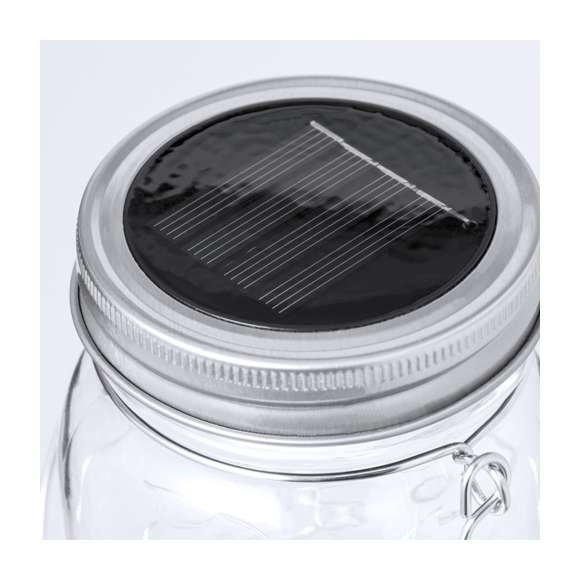 Original lámpara tarro solar, fabricada en resistente material cristal y con una tira interior decorativa de 20 LEDs. Incluye tapadera a rosca metálica con minipanel solar de recarga integrado y una batería recargable de 300 mAh. Con práctica asa para transportar o colgar, y presentada en caja individual de diseño kraft.