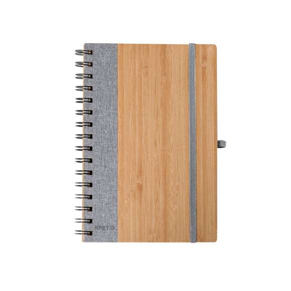 Libreta de anillas con tapas rígidas de bambú. Incluye 80 hojas con disposición a una raya de papel reciclado. Con cierre elástico, banda lateral, y soporte para bolígrafo a juego. Disponible en variada gama de colores, presentada individualmente en bolsa de papel reciclado. Materiales como el bambú fomentan la utilización de materias primas naturales, reduciendo las emisiones contaminantes. Proviene de una planta de gran resistencia y versatilidad, con crecimiento y regeneración rápidos, siendo una excelente alternativa al uso de madera tradicional.