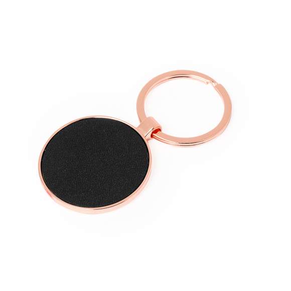Llavero metálico de sofisticado diseño, con recubrimiento de cobre galvanizado y acabado brillo. Forrado en elegante polipiel en una de sus caras y disponible en diseño rectangular y circular. Presentado individualmente bolsa de papel reciclado.