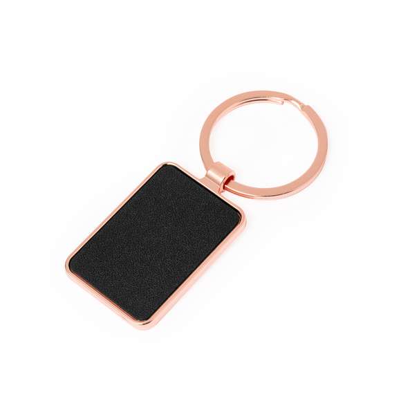 Llavero metálico de sofisticado diseño, con recubrimiento de cobre galvanizado y acabado brillo. Forrado en elegante polipiel en una de sus caras y disponible en diseño rectangular y circular. Presentado individualmente bolsa de papel reciclado.