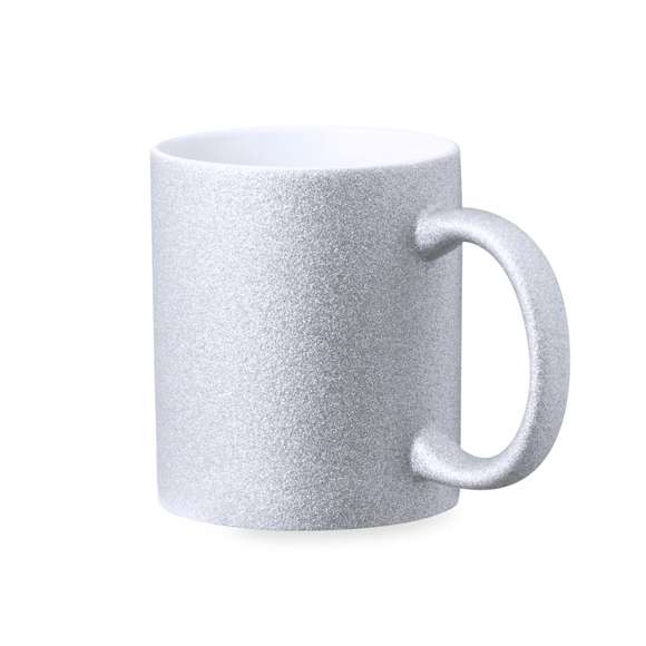 Taza de cerámica con 350 ml de capacidad. Original cobertura efecto purpurina y especialmente diseñada para marcaje en sublimación. Disponible en plata y presentada en caja individual kraft.