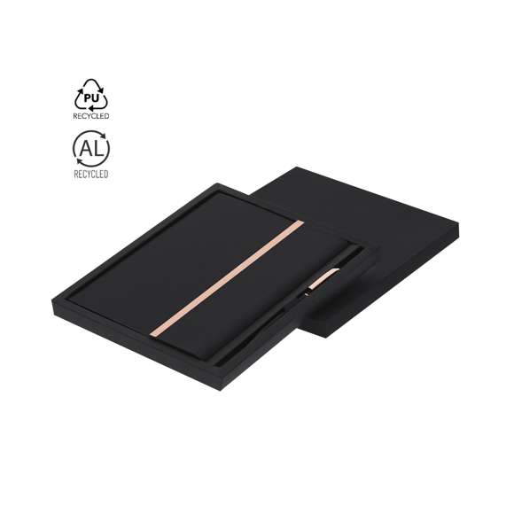 Set de bloc de notas y bolígrafo fabricados en PU Reciclado y Aluminio Reciclado. En elegante negro mate y con distinguidos accesorios en acabado oro rosa. El set incluye: - Bloc de notas fabricado en PU Reciclada y elegante detalle en oro rosado, con tapas rígidas y sistema de cierre imantado. Incluye 80 páginas de color crema con líneas, un marcapáginas a juego y soporte para bolígrafo. Con distintivo PU Reciclada. - Bolígrafo de aluminio reciclado, con cuerpo en color negro mate y detalles en acabado oro rosa. Dispone de clip metálico, mecanismo giratorio y tinta azul. Incluye distintivo de aluminio reciclado. Todo el conjunto se presenta en un elegante estuche negro.La PU Reciclada destaca por su resistencia y elasticidad. Este material reciclado y reciclable es una opción sostenible que rescata las fibras desechadas en los procesos de fabricación, minimizando así el desperdicio de material y contribuyendo a su vez a reducir el impacto ambiental, manteniendo a la vez sus propiedades originales.El Aluminio Reciclado es un material con posibilidades de reciclaje casi infinitas, sin perder sus propiedades originales y consumiendo menos energía en este proceso.Certificación GRS (Global Recycled Standard / Estándar de Reciclaje Global), que garantiza el origen reciclado del material usado para fabricar el producto.