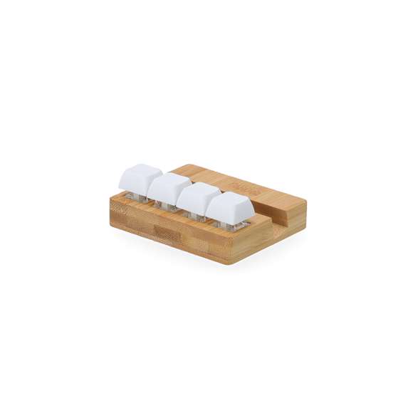 Original soporte antiestrés fabricado en bambú. Cuenta con cuatro teclas que imitan a un teclado mecánico, permitiendo pulsarlas de forma independiente tantas veces como sea necesario. Incluye un práctico soporte para dispositivos móviles, combinando funcionalidad y alivio del estrés en un elegante diseño.Materiales como el Bambú fomentan la utilización de materias primas naturales, reduciendo las emisiones contaminantes. Proviene de una planta de gran resistencia y versatilidad, con crecimiento y regeneración rápidos, siendo una excelente alternativa al uso de madera tradicional.