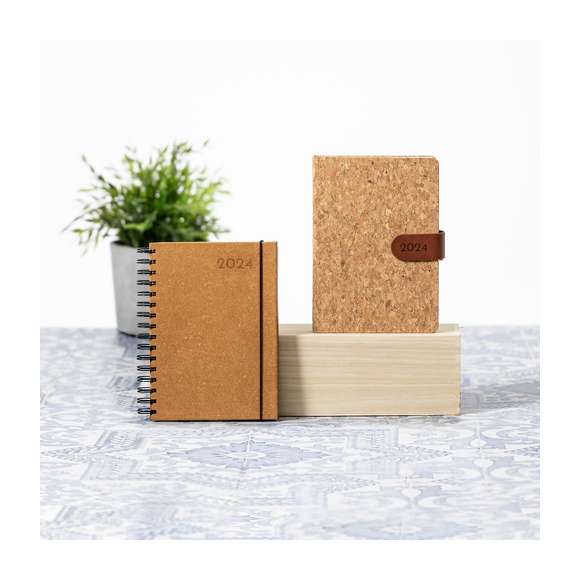 Agenda de tamaño A5 fabricada en elegante y sostenible cuero reciclado. Con cubiertas rígidas y elástico de cierre. Con distintivo cuero reciclado.Diseño página día, zona de anotaciones por día y páginas con esquina troquelada para marcar el día. En 2 idiomas: castellano e inglés. Presentado en caja kraft. El cuero reciclado rescata las fibras desechadas en los procesos de fabricación del cuero, minimizando el desperdicio de material, contribuyendo a reducir el impacto ambiental y manteniendo a la vez sus propiedades originales.