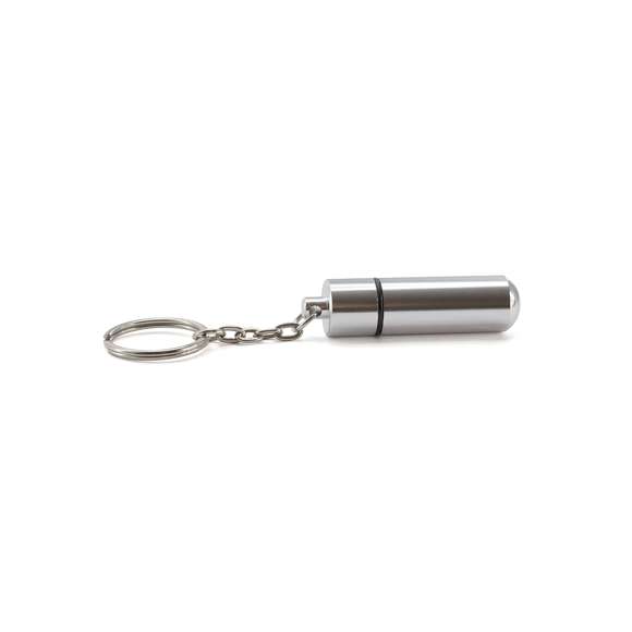 Llavero pastillero de discreto diseño con cuerpo en aluminio de acabado brillante y cierre a rosca.