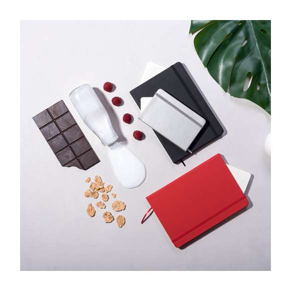 Bloc de notas con tapas duras fabricado en polipiel de suave tacto. Con marcapáginas disponible en variada gama de colores y elástico de cierre a juego. Interior con 100 hojas lisas.