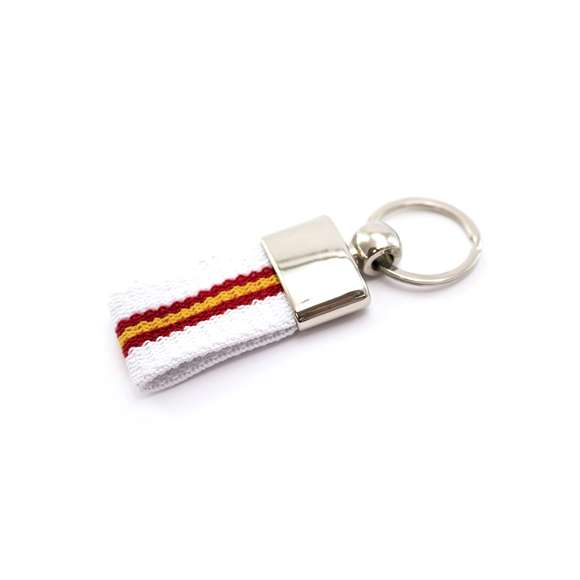 Llavero de poliéster con accesorios de bandera española en la cinta y refuerzo metálico en acabado plateado brillante.