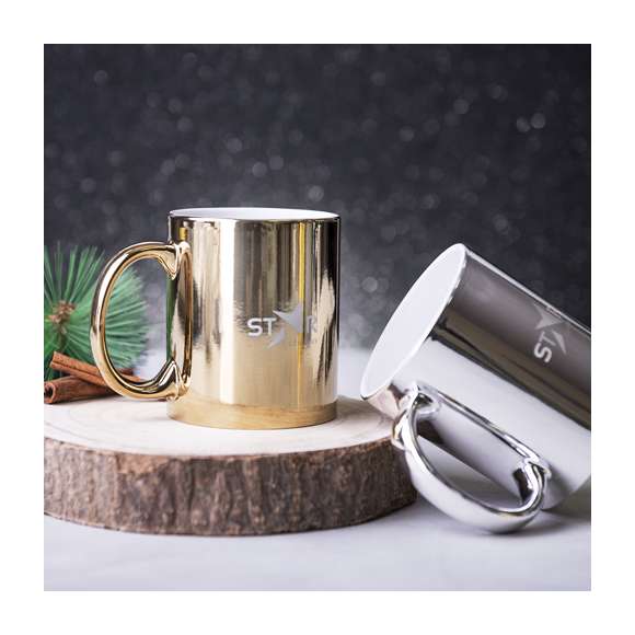 Taza de cerámica de 350ml de capacidad. Disponible en llamativos colores plateado y dorado brillantes. Especialmente diseñada para marcaje en láser, con un recubrimiento exterior metalizado especial para que tu publicidad quede perfectamente grabada en color blanco, a juego con el color interior de la taza. Presentada en caja individual. Se desaconseja su uso en el microondas debido al recubrimiento exterior metalizado.