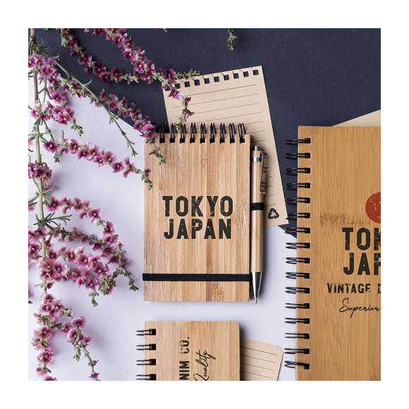  	Libreta de anillas en línea nature con tapas rígidas de bambú y bolígrafo a juego, también en bambú. De tamaño compacto, con elástico de cierre en elegante color negro. Incluye 70 hojas con disposición a una raya y diseño eco. Bolígrafo con cartucho jumbo y tinta azul.
