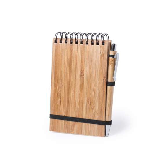  	Libreta de anillas en línea nature con tapas rígidas de bambú y bolígrafo a juego, también en bambú. De tamaño compacto, con elástico de cierre en elegante color negro. Incluye 70 hojas con disposición a una raya y diseño eco. Bolígrafo con cartucho jumbo y tinta azul.