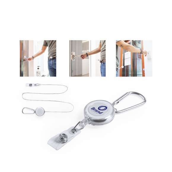 Porta objetos extensible de sobrio diseño, con cinta de fijación de cierre de botón y mecanismo extensible de hasta 65 cm. Incluye mosquetón metálico de enganche. Especialmente diseñado para fijar objetos de uso cotidiano y obtener fácil acceso a los mismos (llaveros anticontacto, punteros de seguridad...). Amplia superficie de marcaje en la pieza central.