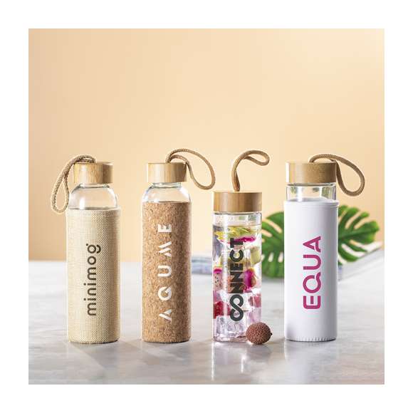 Bidón de línea nature en combinación de materiales bambú y cristal. 500 ml de capacidad, con tapón a rosca en bambú y funda en acabado de inspiración eco. Asa de transporte en color nature y presentado en atractiva caja de diseño eco. Disponible manual de instrucciones en español e inglés.