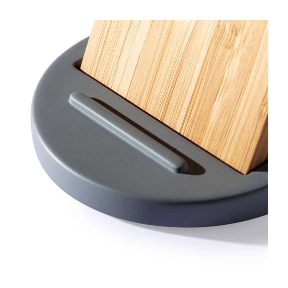 Cargador inalámbrico con función soporte para smartphone. Fabricado en combinación de piezas de bambú de corte nature y cemento de piedra caliza, un conglomerante formado por la mezcla de materiales naturales, principalmente piedra caliza molida y agua, obteniendo un material de gran consistencia y durabilidad.  Indicador led, cable de carga USB a juego y compatible con dispositivos equipados con tecnología de carga inalámbrica. Protección de seguridad para evitar sobrecalentamiento, sobrecarga y cortocircuito. Presentado en atractiva caja de diseño.