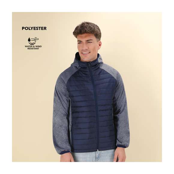 Chaqueta unisex transpirable en combinación de materiales soft shell y poliéster, con tejido acolchado tacto pluma en frontal y espalda. Capucha y manga estilo ranglán con ribete elástico en cuello, puños y bajo . De elegante construcción en combinación de colores negro y gris, resistente al viento y al agua. Cierre de cremallera y bolsillos laterales de cremallera con tiradores para fácil apertura. Disponible en tallas S, M, L, XL, XXL.