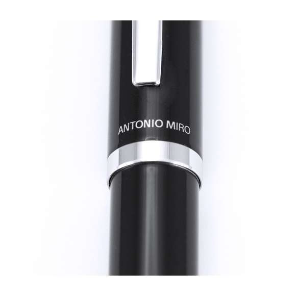 Bolígrafo de Antonio Miró en elegante diseño bicolor y suave cuerpo metálico en sobrio color negro. Con logotipo de la marca encima de la anilla, clip y punta en acabado plateado brillante. Presentado en estuche individual en color negro con logotipo de la marca. De cartucho jumbo con tinta azul.