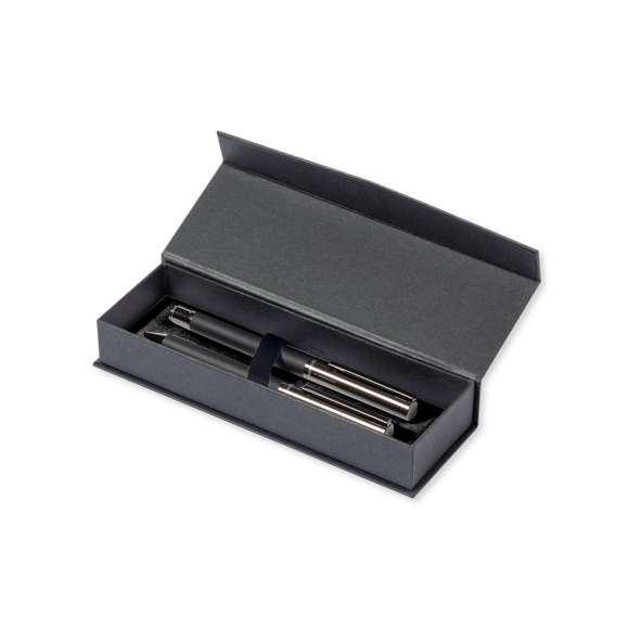 Set de bolígrafo y roller de Antonio Miró. Incluye: Bolígrafo metálico con cuerpo en negro mate. Detalles y capucha en cromado con logotipo de la marca  cartucho jumbo y en tinta azul.Roller metálico con cuerpo en negro mate. Detalles y capucha en cromado con logotipo de la marca. Cartucho jumbo y en tinta azul.Presentado en elegante y resistente estuche individual negro con logotipo Antonio Miró, cierre magnético y funda de protección a juego.